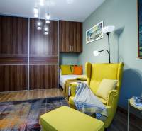 Ein Zimmer mit einem bequemen Sessel, einem Kleiderschrank, einem Kronleuchter und einem Boden mit Holzdekor in einem Einfamilienhaus.