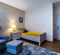 Ein Zimmer im Familienhaus mit einem Sessel, einem Bett, einem Nachttisch und einem Boden mit Holzdekor.