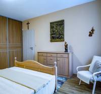 Schlafzimmer in einem Einfamilienhaus mit Holzmöbeln, Bett, Schrank, Sessel, Boden mit Holzdekor.