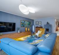 Wohnzimmer in einem Einfamilienhaus mit einem blauen Sofa, einem Boden in Holzoptik und einem Fernseher.