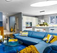 Wohnzimmer in einem Einfamilienhaus mit blauer Couch und Küche, Holzboden.