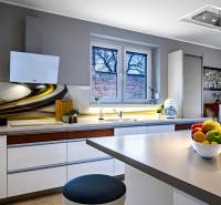 Küche im Einfamilienhaus mit stilvoller Arbeitsplatte, weißen Schränken und Dekorationen am Fenster.