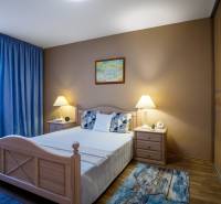 Schlafzimmer im Einfamilienhaus mit Bett, Nachttischen und Boden in Holzoptik.