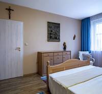Schlafzimmer mit Holzboden in einem Einfamilienhaus, Holzbett und Kommode.