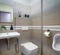 Ein Badezimmer in einem Einfamilienhaus mit Waschbecken, Toilette und Fliesen in neutralen Tönen.