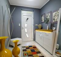 Eingangshalle eines Einfamilienhauses, weiße Möbel, gelbe Vasen und ein bunter Teppich.