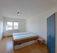 Schlafzimmer in einer 4-Zimmer-Wohnung mit Bett, Schrank und Boden in Holzoptik.