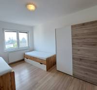 Ein Zimmer in einer 4-Zimmer-Wohnung mit zwei Betten und einem Boden in Holzoptik.