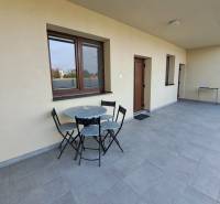 Eine Terrasse mit Sitzgelegenheiten in einer 4-Zimmer-Wohnung mit gefliestem Boden und hellen Wänden.