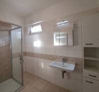 Badezimmer mit Dusche, Waschbecken und Fliesen in einer 4-Zimmer-Wohnung.