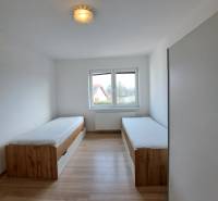Ein Zimmer in einer 4-Zimmer-Wohnung mit zwei Betten und einem Boden in Holzoptik.