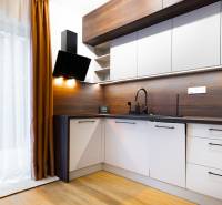 Küche in einer Einzimmerwohnung mit Holzboden, Vorhang und modernen Geräten.