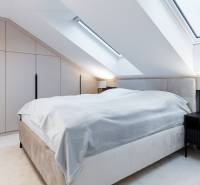 Ein Schlafzimmer im Dachgeschoss mit einem großen Bett, einem Nachttisch und einem Einbauschrank.
