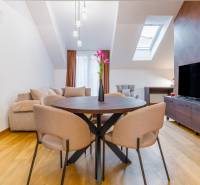 Innenraum einer Einzimmerwohnung mit Tisch, Sofa und Boden in Holzoptik.