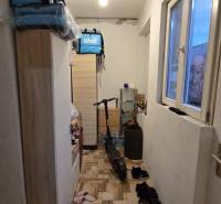 Ein enger Flur in einem Einfamilienhaus mit Regalen, einem Fenster, einem Elektroroller und Schuhen.