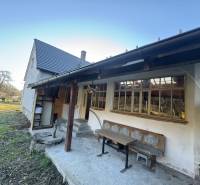 Ein Einfamilienhaus in Demandice mit Garten, Holzbänken und einem Außenbereich zum Sitzen.