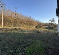 Garten beim Einfamilienhaus in Demandice mit Bäumen und einer weitläufigen Rasenfläche.