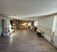 Innenraum eines Einfamilienhauses mit Küchenzeile, gemauertem Ofen und Boden in Holzoptik.