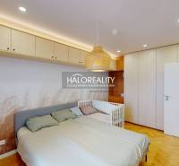 Schlafzimmer in einer 3-Zimmer-Wohnung mit Einbauschränken, Bett und Kinderbett.