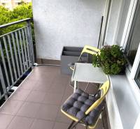Balkon einer 2-Zimmer-Wohnung in Bratislava mit Stühlen und Grünpflanzen, geeignet zum Entspannen.