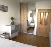 Schlafzimmer in einer 2-Zimmer-Wohnung mit Holzboden, Einbauschrank und Kommode.