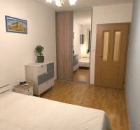 Schlafzimmer in einer 2-Zimmer-Wohnung mit Holzboden, Schränken mit Spiegel und Bild.