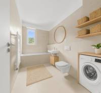 Badezimmer mit Badewanne, Waschbecken, Spiegel und Waschmaschine in einer Zweizimmerwohnung.