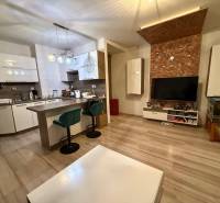 Wohnzimmer mit Küche, Bartresen und Holzboden in einer Zweizimmerwohnung.