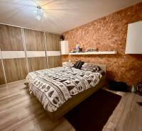 Schlafzimmer in einer 2-Zimmer-Wohnung mit Bett, Stauraum und Boden mit Holzdekor.