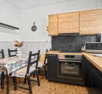 Eine Küche mit Holzdekor, Esstisch und Geräten in einer 3-Zimmer-Wohnung.