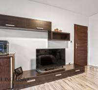 Wohnzimmer in einer 3-Zimmer-Wohnung mit Holzboden und großem Fernseher.