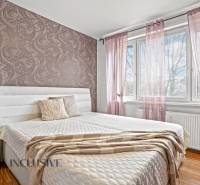 Schlafzimmer in einer 3-Zimmer-Wohnung mit dekorativer Tapete und Bodenbelag in Holzoptik.