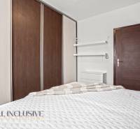 Schlafzimmer in einer 3-Zimmer-Wohnung mit Bett, Einbauschrank und minimalistischen Regalen.