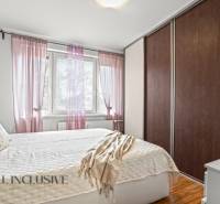 Schlafzimmer in einer 3-Zimmer-Wohnung mit Bett, Schrank und dekorativen Kissen, Boden mit Holzdekor.