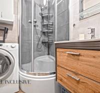 Badezimmer mit Waschmaschine, Duschkabine und Schrank in einer 3-Zimmer-Wohnung.