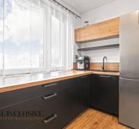 Küche in einer 3-Zimmer-Wohnung mit großem Fenster, schwarzen Schränken und Boden mit Holzdekor.