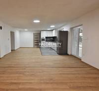 Wohnzimmer in einem Einfamilienhaus mit Küche, Holzboden, weiße Wände.