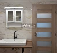 Badezimmer mit Waschbecken, schwarzem Wasserhahn und Schrank in einem Einfamilienhaus.