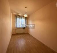 Ein enger, heller Raum mit einem Fenster, Vorhängen und einem Boden mit Holzdekor in einer 3-Zimmer-Wohnung.