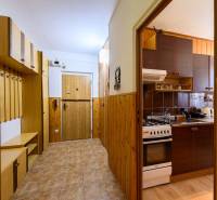 Der Flur und die Küche in einer Zweizimmerwohnung mit Holzdekor und Stauraum.