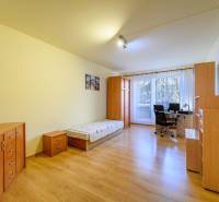 Ein Zimmer in einer 2-Zimmer-Wohnung; Bett, Schreibtisch, Schränke, Boden mit Holzdekor.