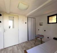 Einfaches Interieur, weißes Ferienhaus, kleiner Tisch, heller Boden, Tür mit Fenster, Erholungsraum.