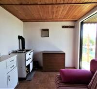 In der Chatküche gibt es einen Ofen, einen Schrank, ein rosa Sofa und einen Blick auf den Garten.