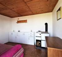 Ein Raum mit einem Herd, Schränken und einem Sofa, der durch die Holzdecke der Hütte gemütlich wird.