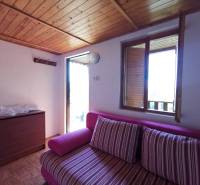 Ein Zimmer in einer Hütte mit einem rosa Sofa, einer Holzdecke und einem Blick aus dem offenen Fenster.