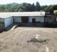 An der Straße Železničná befinden sich Lagerhallen, umgeben von Grünflächen, die zur Nutzung geeignet sind.