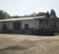 Lagerhäuser und Hallen in der Železničná-Straße in Veľký Krtíš, umgeben von Bäumen.