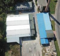 Luftaufnahme von Hallen und Lagern in der Nähe der Straße Železničná, umgeben von Grünflächen und Grundstücken.