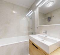 Badezimmer in einer 3-Zimmer-Wohnung mit Fliesen, Badewanne, Waschbecken und Spiegel.