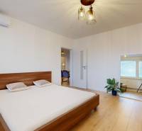 Schlafzimmer in einer 3-Zimmer-Wohnung mit Bett, Spiegel und Boden in Holzoptik.